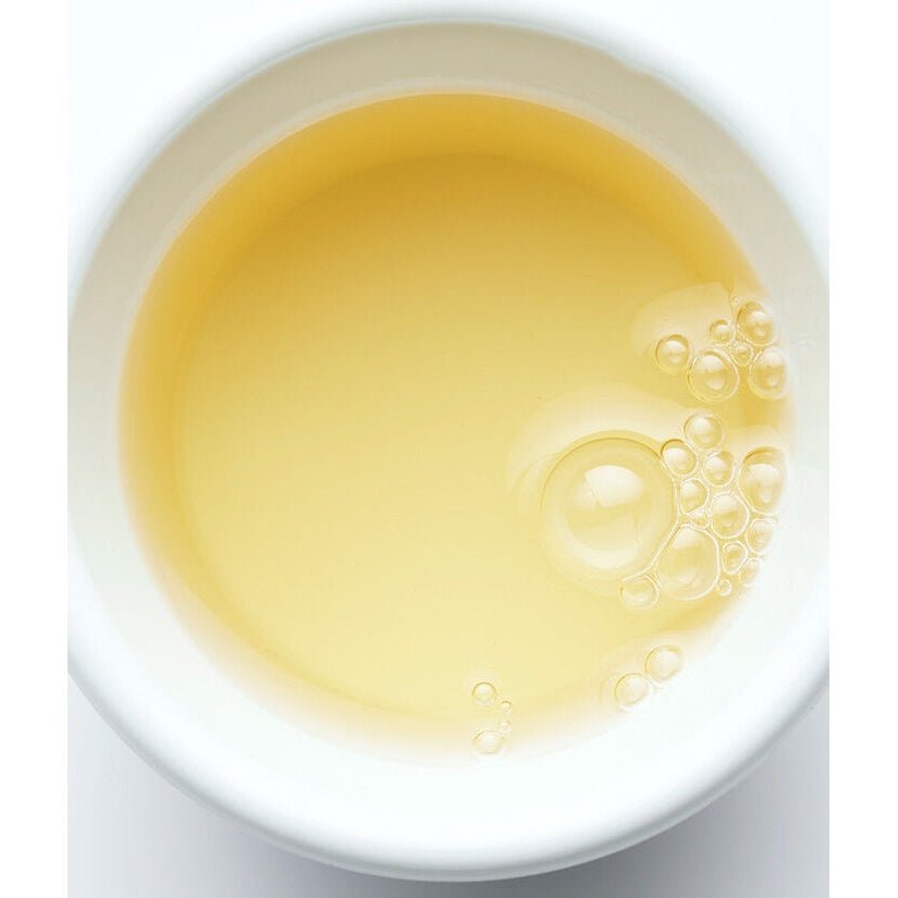 A white bowl filled with a light yellow liquid, showing some bubbles on the surface.