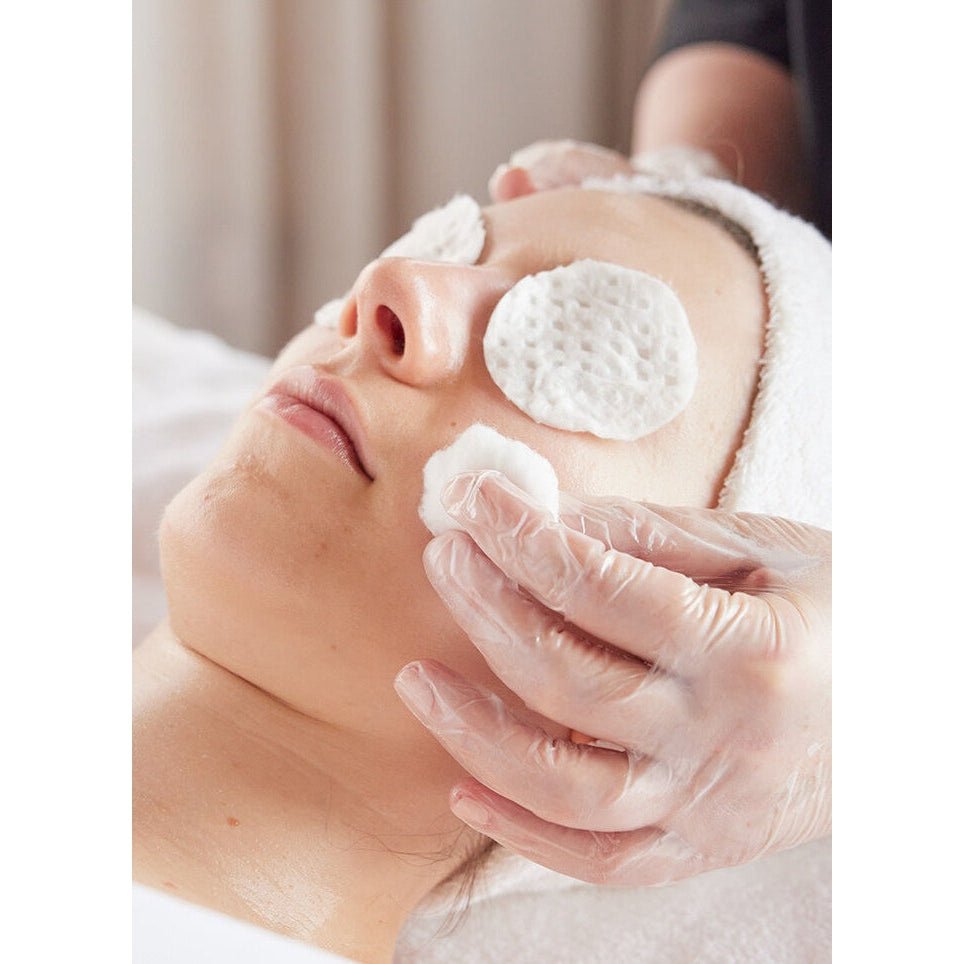 A person receives a facial treatment with cotton pads on their face.
