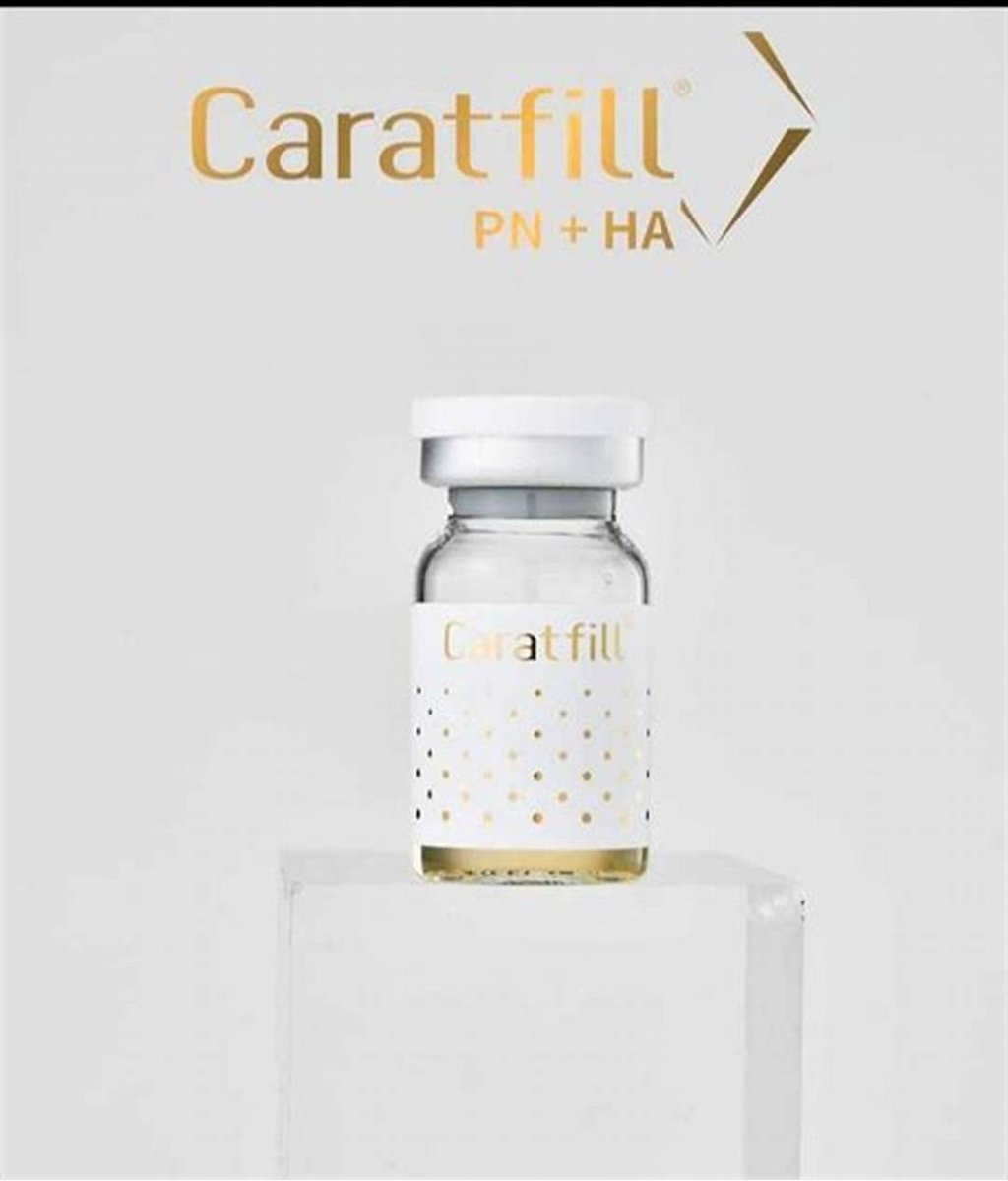 A Caratfill Skinbooster vial with a gold label and text sits on a white pedestal.